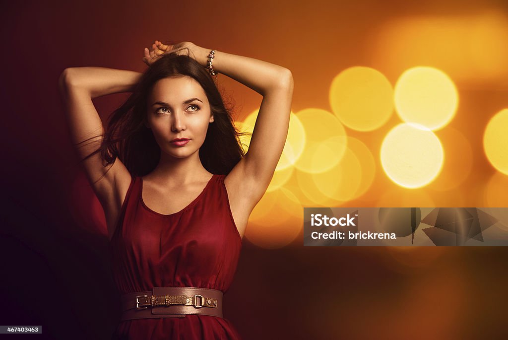 Beautiful Young Woman over Bright Night Lights Portrait of a Beautiful Young Woman in Fashionable Red Dress over Bright Night Lights. Nightlife Party Concept. Adult Stock Photo