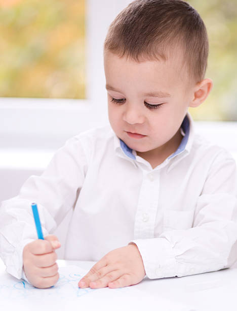 istock Little boy is drawing on white paper 467404205