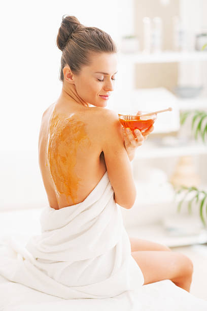 istock young woman sitting on massage table with honey plate 467405467