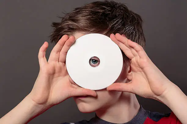 teenage boy is looking through the hole of a white disc, with gray background for fast isolating