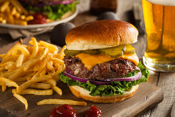 huge grass fed bison hamburger with chips & beer - gegrild fotos stockfoto's en -beelden