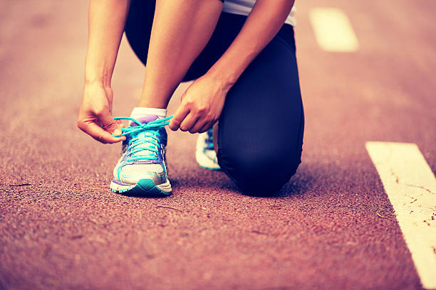 istock woman runner tying shoelaces on trail 467425506