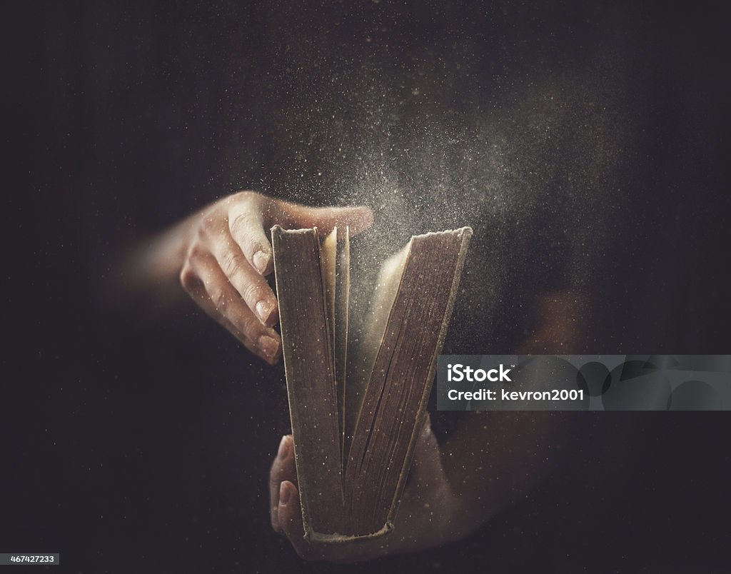 Old Dusty Book Holding an open book with dust coming out. Book Stock Photo