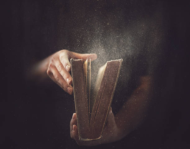 Old Dusty Book Holding an open book with dust coming out. dust book stock pictures, royalty-free photos & images