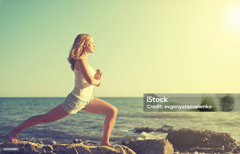 young woman doing yoga on  beach young woman  doing yoga on  coast of  sea on  beach Active Lifestyle Stock Photo