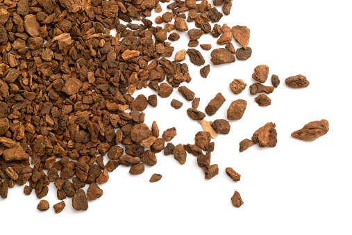 Dandelion coffee granules, made from roasting dandelion root,  scattered across a white background.