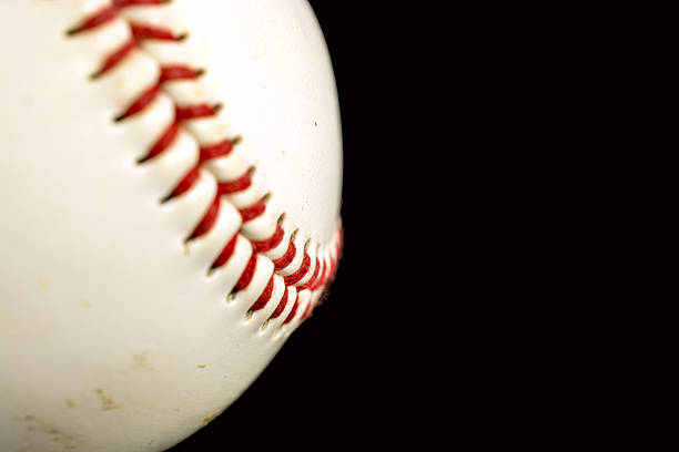 istock Baseball close-up showing stitches with copy space room. Black background 467434242