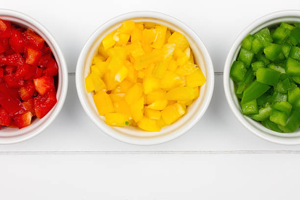 three white bowls with sliced colorful paprikas
