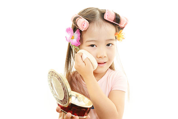 Preschool girl playing with makeup isolated on white background