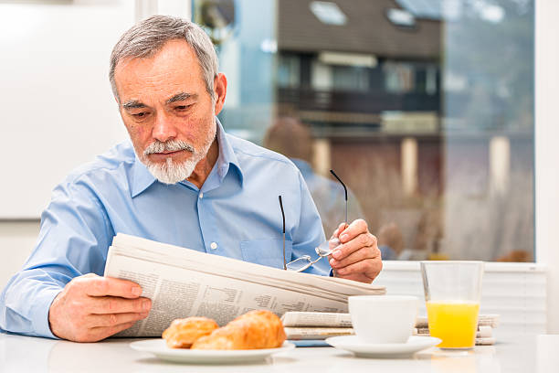 hombre mayor leyendo un periódico - hotel newspaper coffee reading fotografías e imágenes de stock