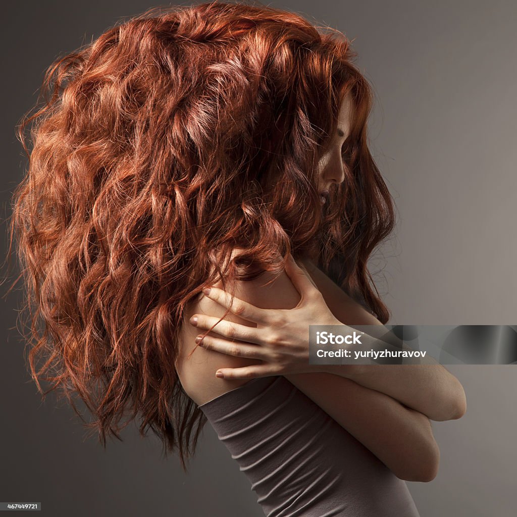 Beautiful woman with curly hairstyle against gray background Volume - Fluid Capacity Stock Photo