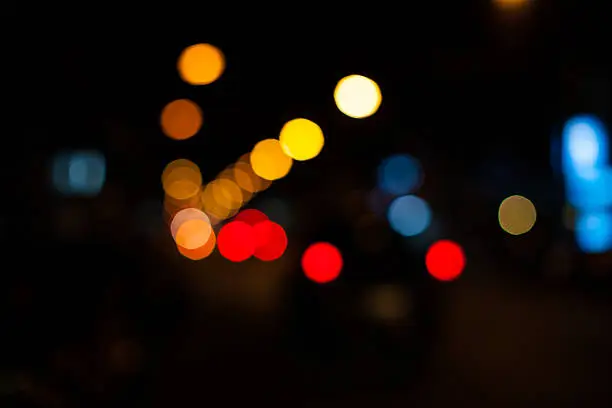Bright circles from streetlamps on defocused photo of night street.