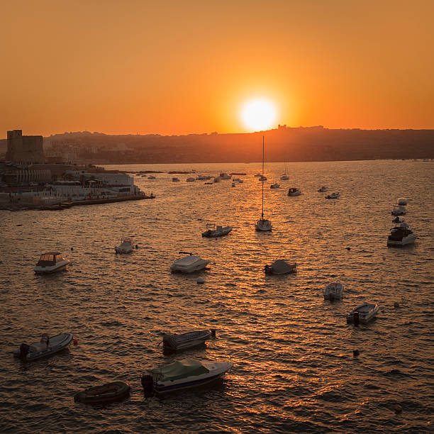 Sunset view over St Paul's Bay in Malta. The fortified Selmun Palace can be seen on top of the hill.