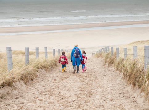 woman and two small children walking down to the beach