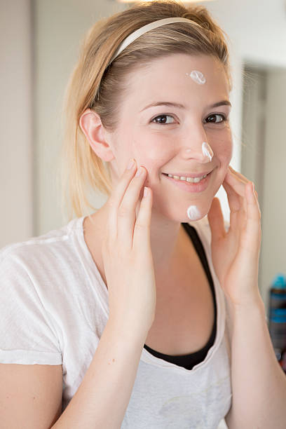 Young woman creaming her face Young woman creaming her face creaming stock pictures, royalty-free photos & images