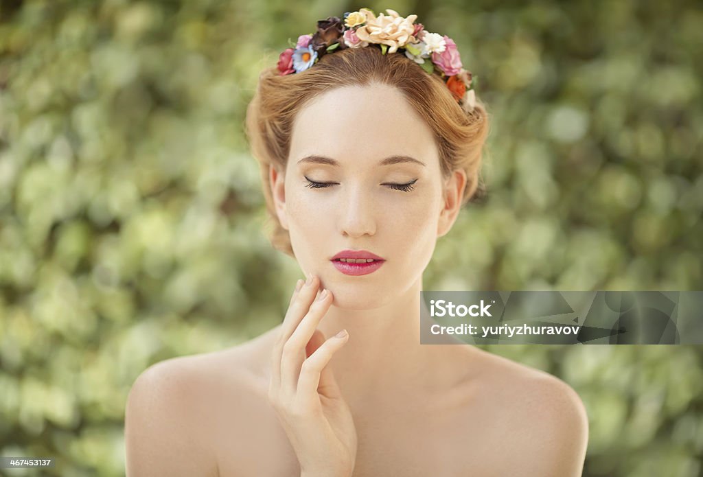 Beautiful young woman with flowers wreath in hair Beautiful young woman with flowers wreath in hair on natural green background Adult Stock Photo