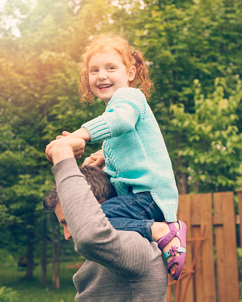 istock Happy kid up on dad shoulders in suburban backyard. 467454411