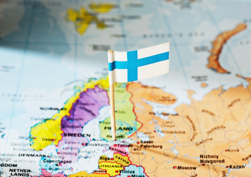 A Finnish national flag is stuck into Finland, marking it on a map of Europe,