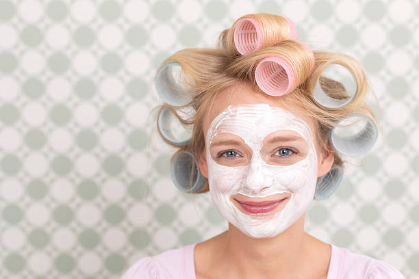 istock Young woman with curlers and face mask, smiling 467455490