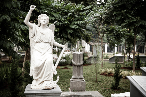 Jakarta, Indonesia - January 11, 2014: Statue of Angel holding sword in old cemetery Museum Prasasti