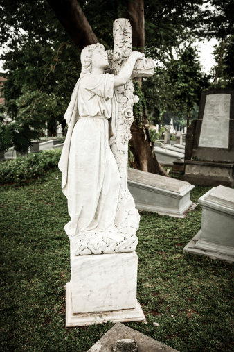 Jakarta, Indonesia - January 11, 2014: Statue of Angel and tombstones in old cemetery Museum Prasasti