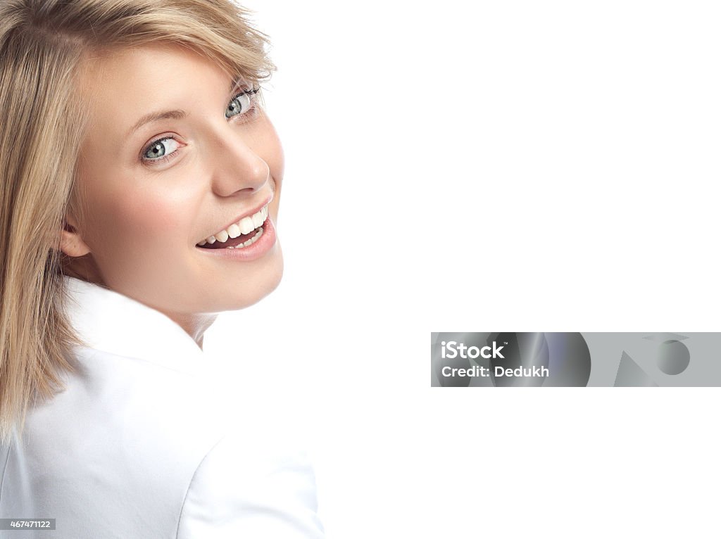 A woman looking over her shoulder and smiling at the camera portrait of attractive young caucasian smiling woman blond isolated on white studio shot looking at camera toothy smile 2015 Stock Photo