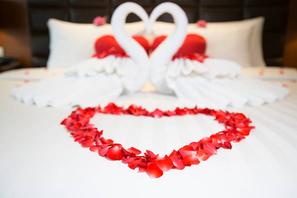 Red and white heart decorations on bed Two swans (made from towels) form a heart on a hotel suite bed, with flowers surrounding them. romantic activity stock pictures, royalty-free photos & images