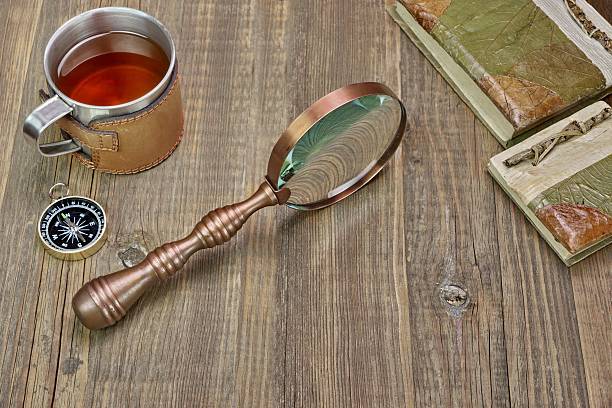 istock Compass, Magnifying Glass, Tea Mug, Two Notebooks on Wood Table 467478346