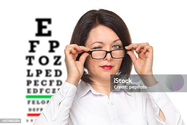 Frau Mit Brille Und Auge Chart Stockfoto und mehr Bilder von Augenuntersuchungen - Augenuntersuchungen, Freisteller – Neutraler Hintergrund, 2015