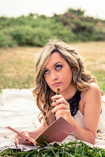 istock Romantic girl with a diary thinking lying down outdoors 467486780