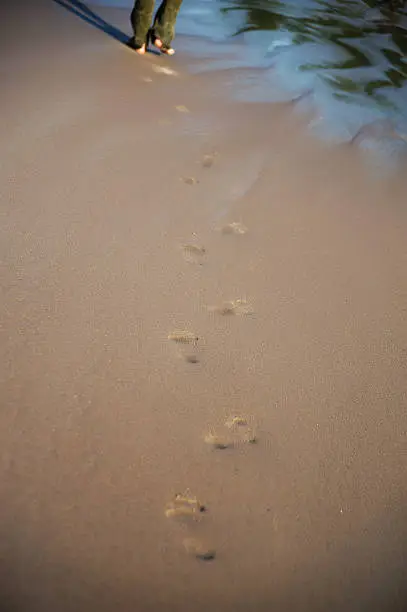 footprints on the wet sand from the male legs on the beach