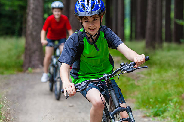 menina e menino adolescente andar de bicicleta nas trilhas da floresta - cycling bicycle mountain bike sport - fotografias e filmes do acervo