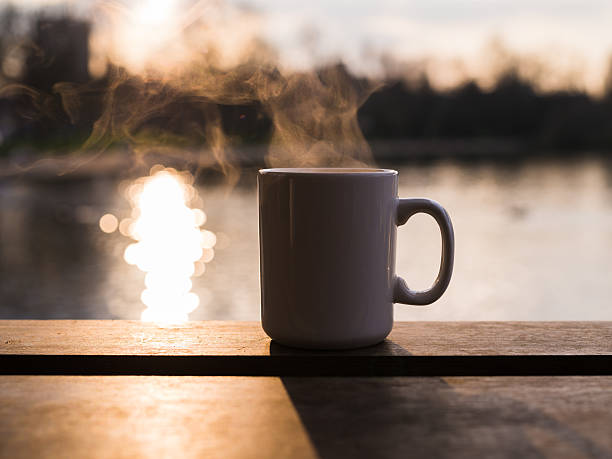 Steam rising from mug by water stock photo