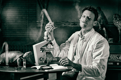 Cliche of an old scientist. Ironically nostalgic image of the scientist who sits with his microscope in smoke and fumes from his experiments