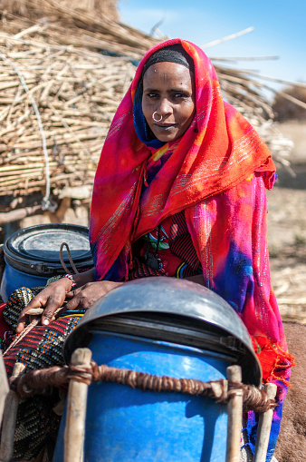 Portrait of an African woman, she seated on the back of a donkey, bogus full of water on each side