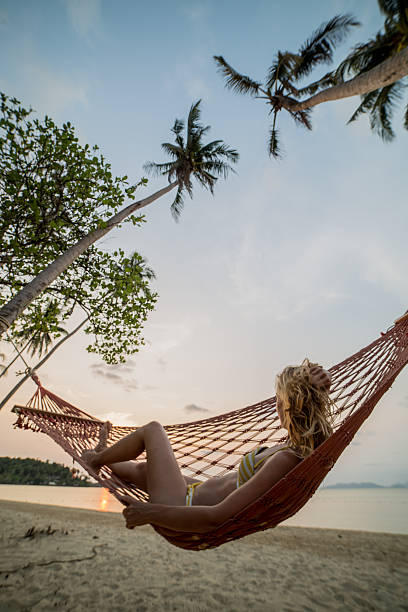istock Young woman watching sunset from hammock 467512746