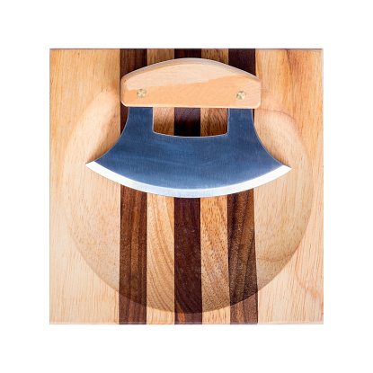 An Alaskan ulu knife is on display over a striped wooden chopping block isolated on white.