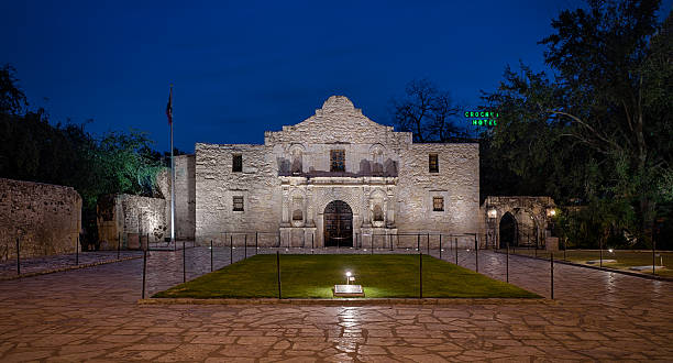 The Alamo San Antonio, Texas, USA - January 7, 2014: The Alamo with the Crockett Hotel neon sign in the background at twilight in San Antonio, Texas sod roof stock pictures, royalty-free photos & images