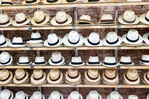 A large number of black, white and tan Panama hats displayed on a shelves.