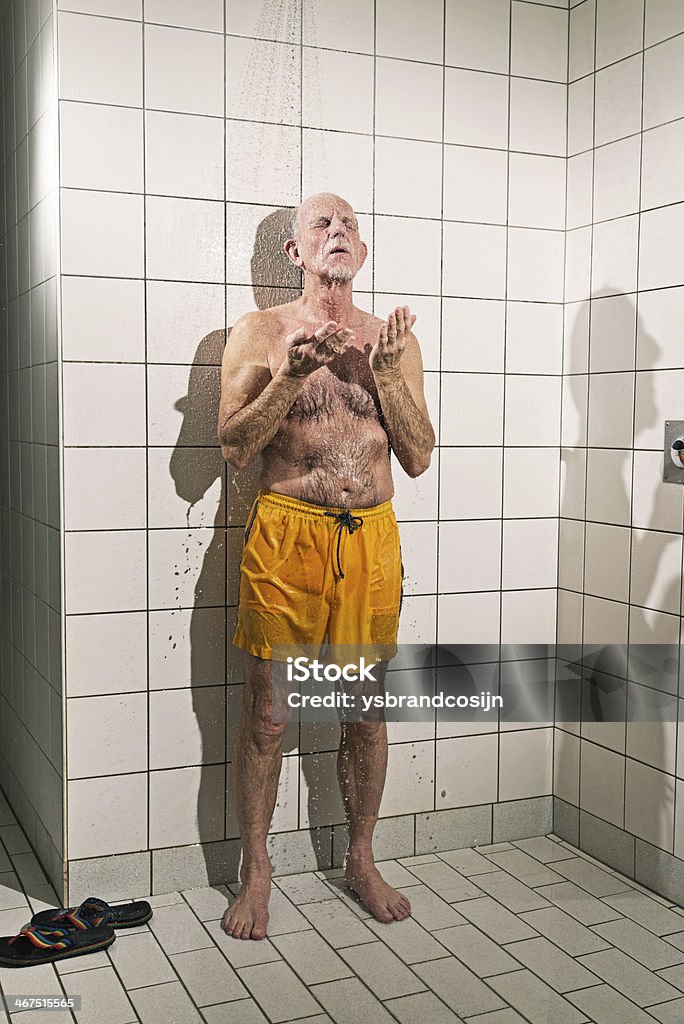Senior man taking a shower in bathroom. Senior man taking a shower in bathroom. Wearing yellow swimming trunks. Senior Adult Stock Photo