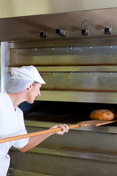 istock Female baker baking fresh bread in the bakehouse 467516121