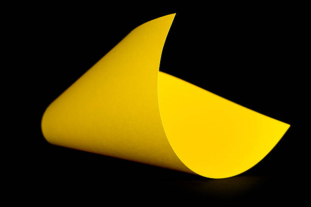 istock Curved yellow paper on a black background- abstract image. 467522046