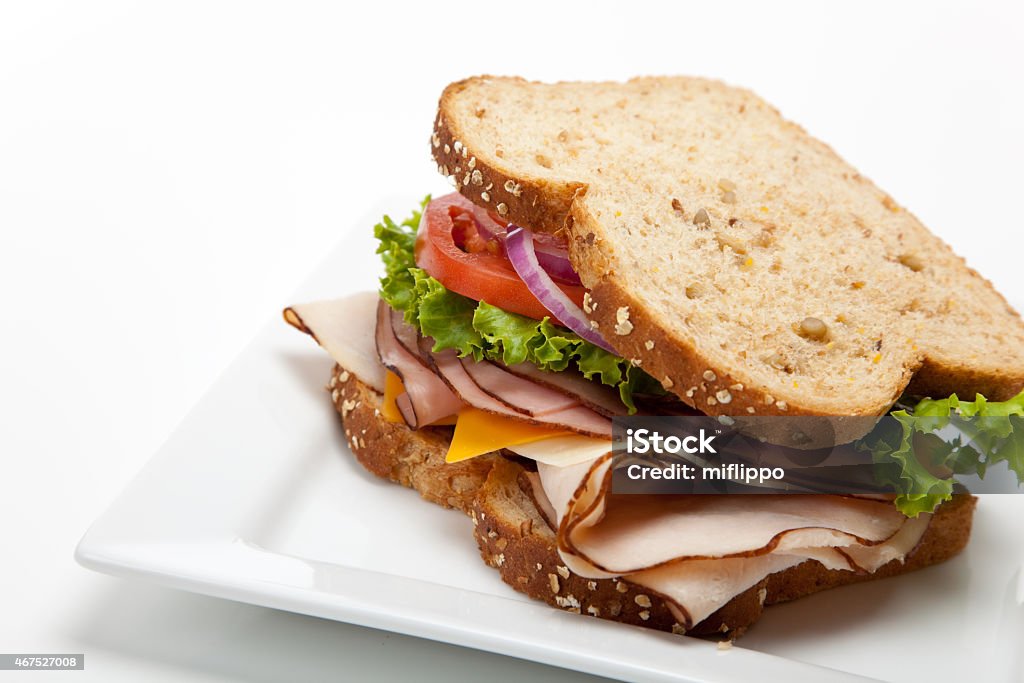 Turkey sandwich on white background A turkey sandwich on multigrain bread with lettuce, tomato, Cheese and onions on a white background Sandwich Stock Photo