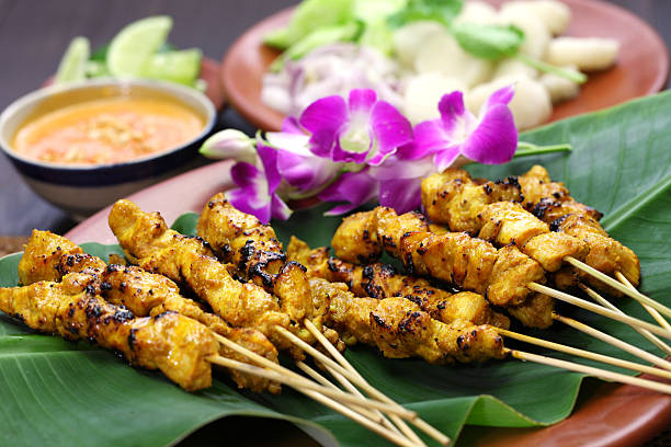 Chicken satay on a banana leaf with purple orchids stock photo
