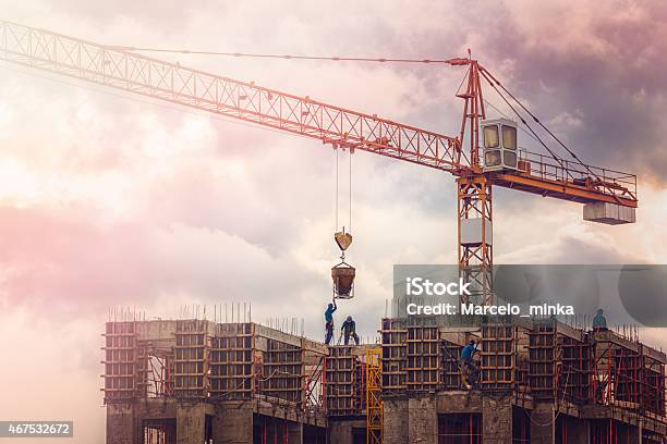 Men Working On High While The Sun Sets Stock Photo - Download Image Now - Crane - Machinery, Blue-collar Worker, Built Structure