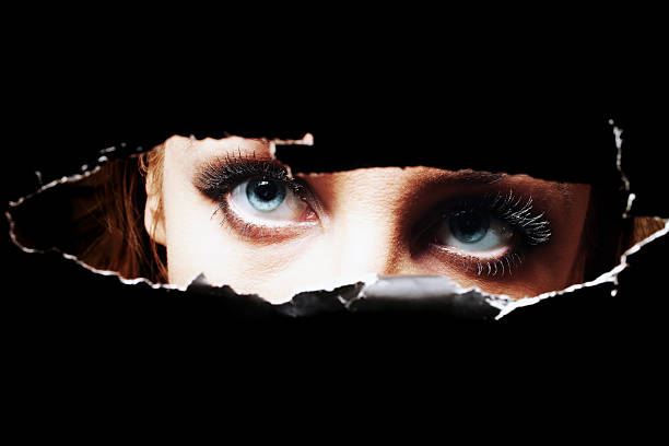 istock Blue eyes of young woman peeping through a hole 467533983