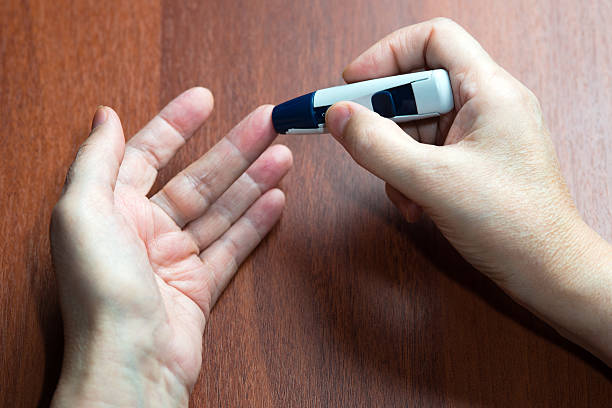 die hand der älteren frau liegt nahe dem gerät - blood sugar test examining instrument of measurement diabetes stock-fotos und bilder
