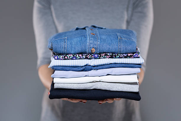 roupas de mulher segurando nas mãos - pile arrangement imagens e fotografias de stock