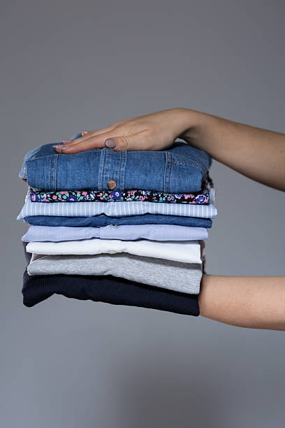 istock Woman holding stack of clothes in hands 467539534