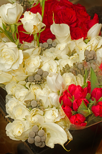 Red and white roses with tulips and grey florals make up this festive arrangement.